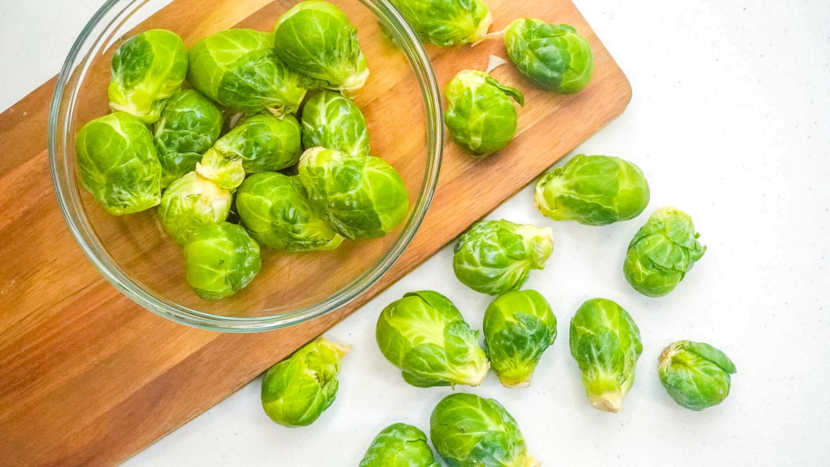 Brussels sprouts in a bowl and on a cutting board.