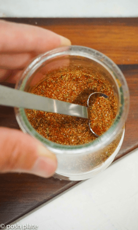 a jar of blackened spice mix recipe with a measuring spoon.