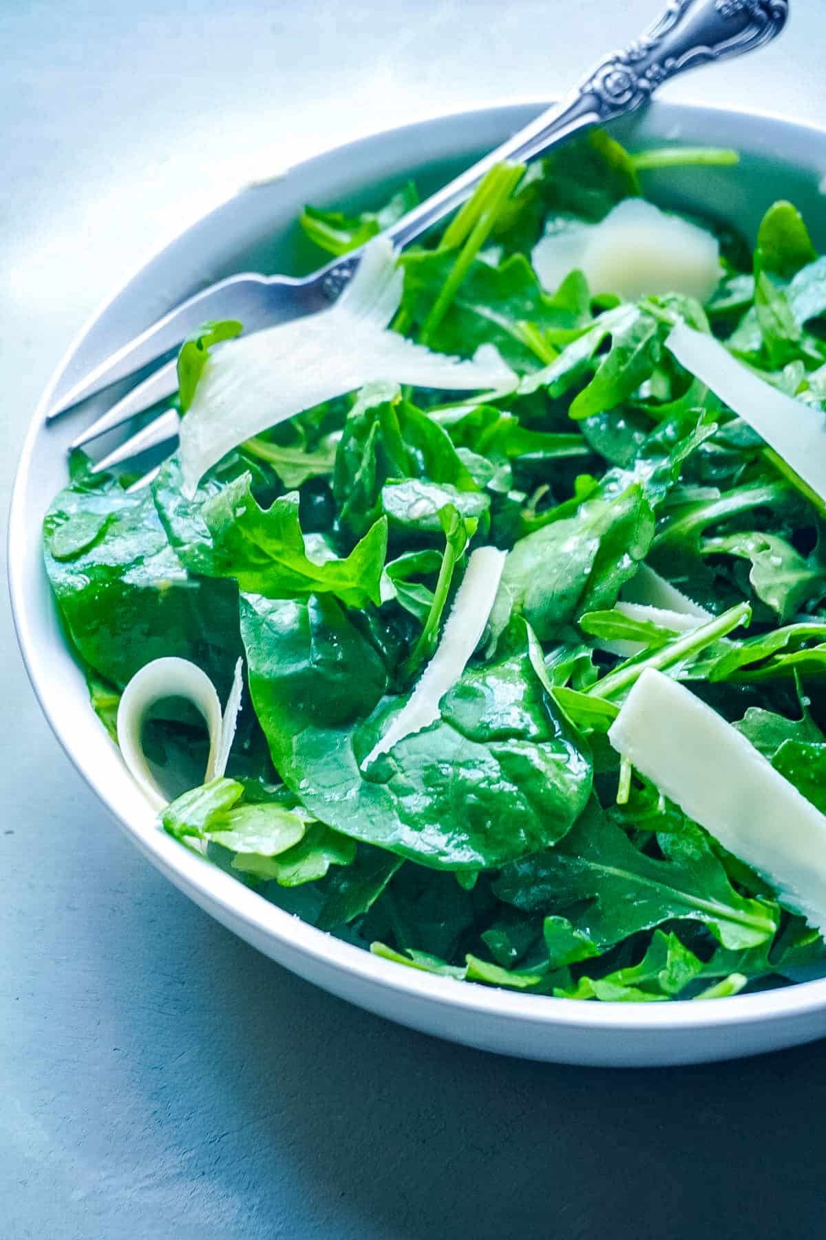 A simple arugula salad with Parmesan Dressing over it.