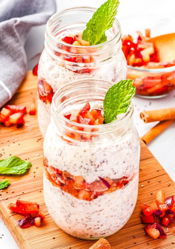 Two plum chia pudding parfaits in a clear glass jar.