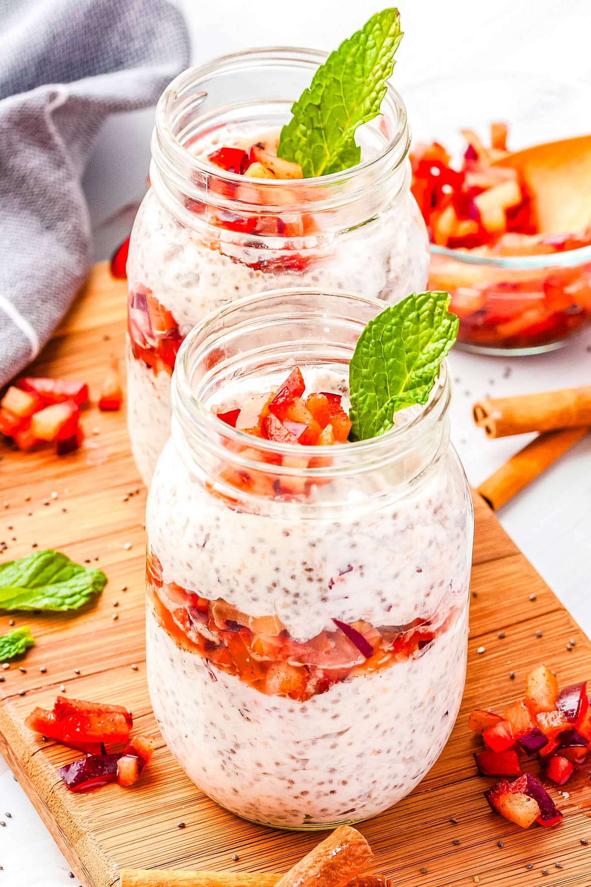 Two plum chia pudding parfaits in a clear glass jar. 