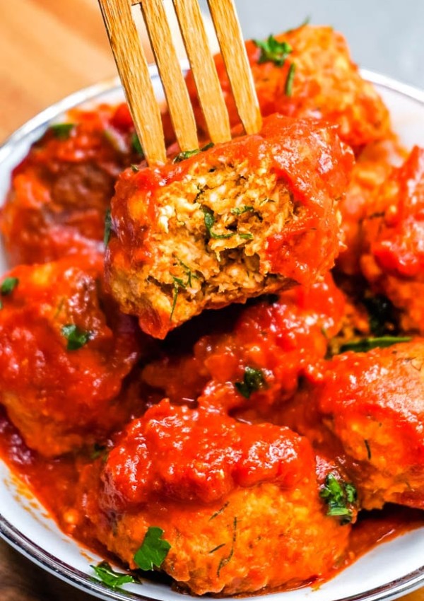 A fork picking up one of the Ajvar Meatballs with a bite taken out of it.