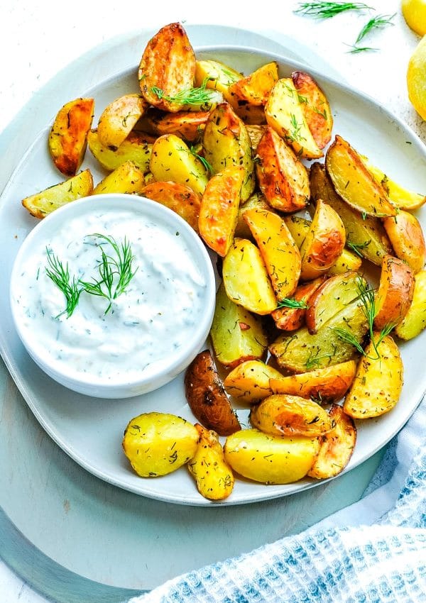 An overhead picture of the finished Dill Roasted Potatoes on a platted with a yogurt dip.