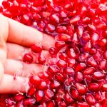 Pomegranate seeds in a bowl full of water.