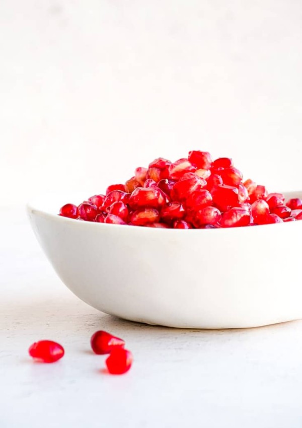 A bowl full of pomegranate seeds on a countertop.