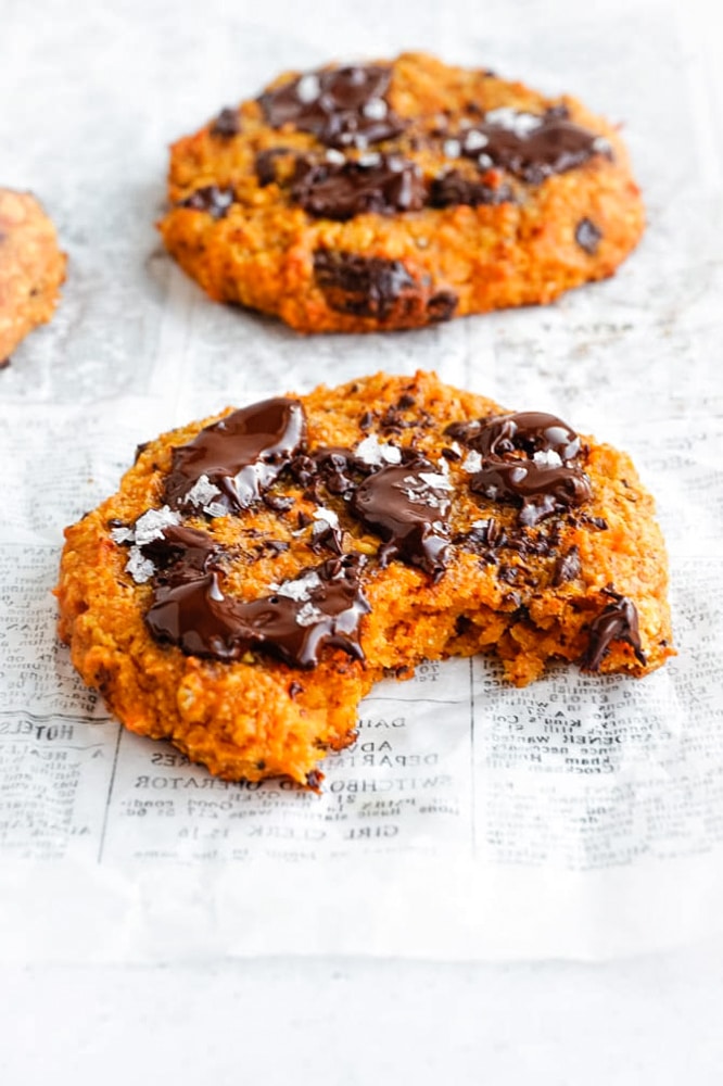 A Sweet Potato Oat Cookie with a bite take out of it and the chocolate on the cookie is nice and melty. 