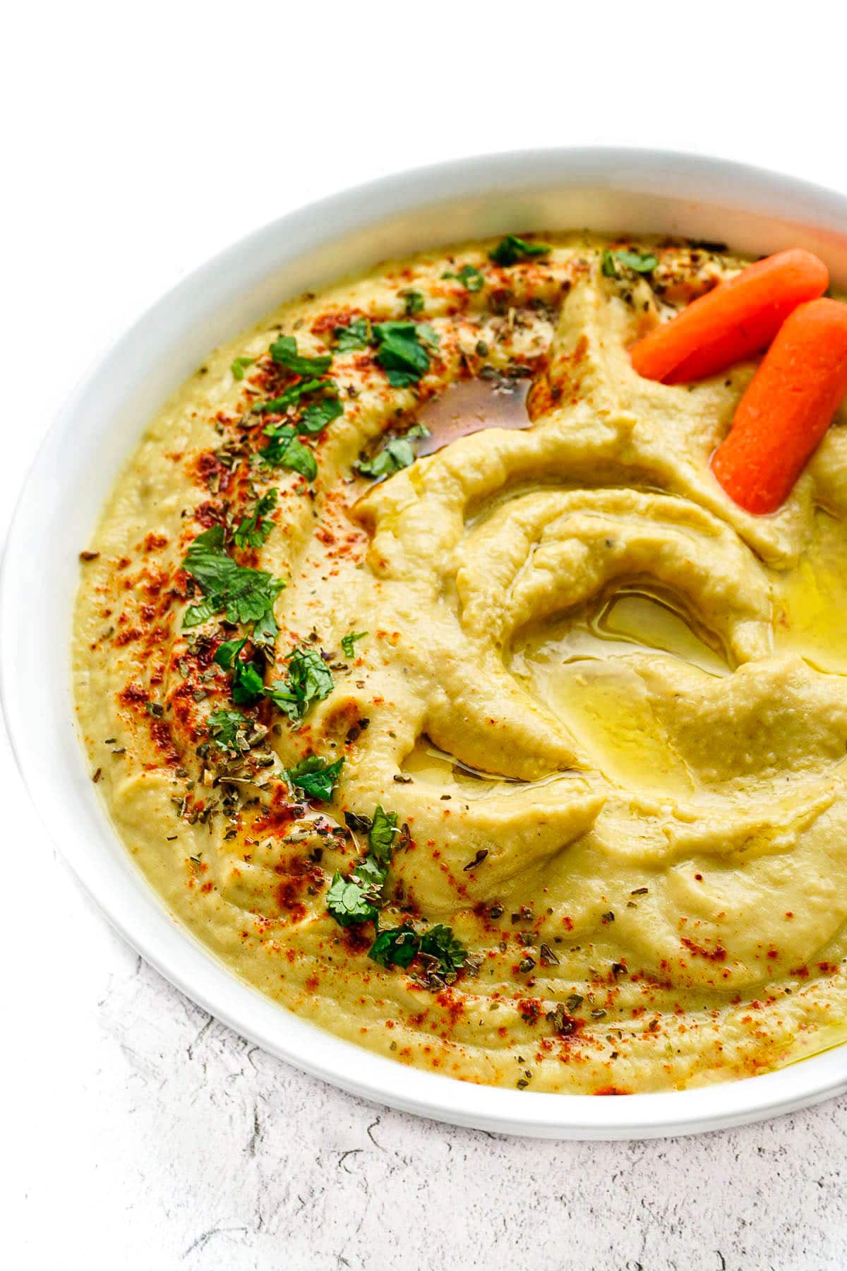 Zucchini Hummus with two baby carrots in the bowl.