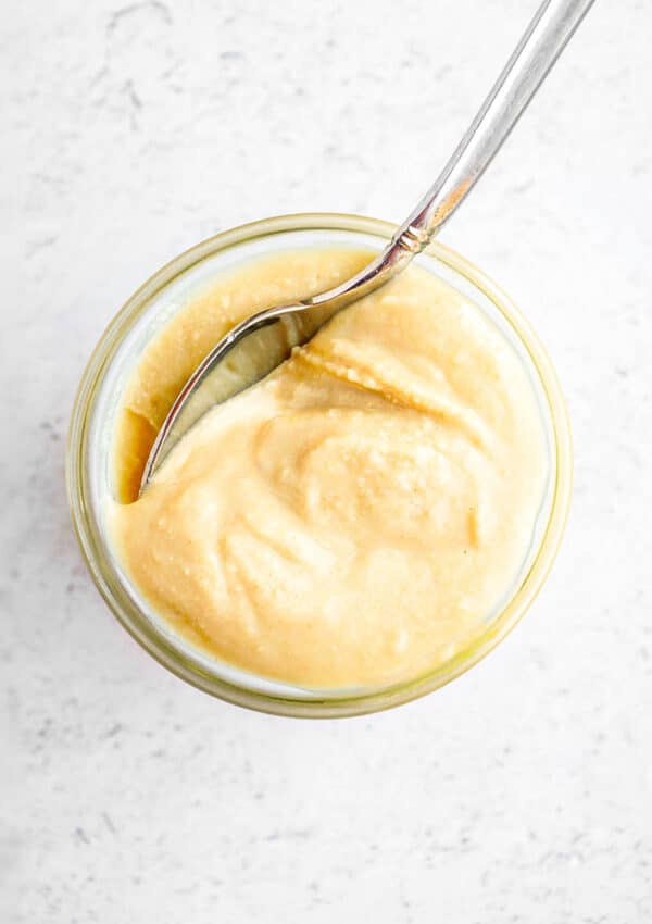 Cashew butter in a glass jar with a spoon in it.