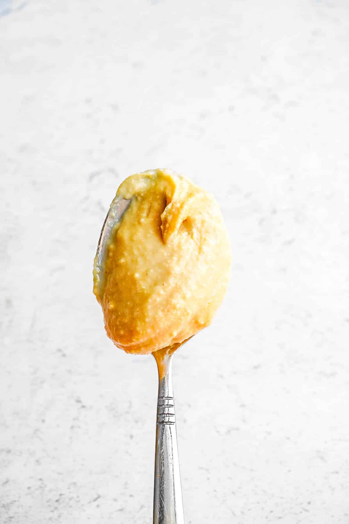 A spoon sticking straight up with cashew butter on it.