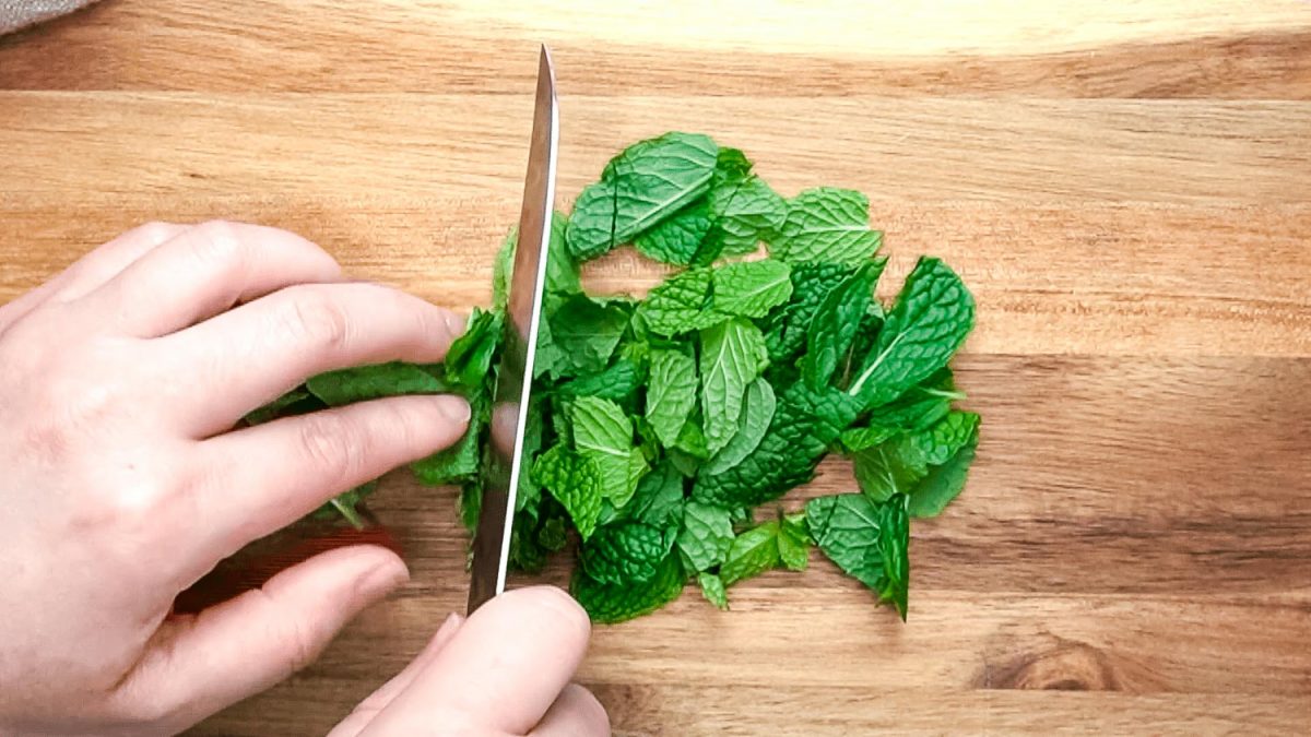 A knife chopping up fresh mint.