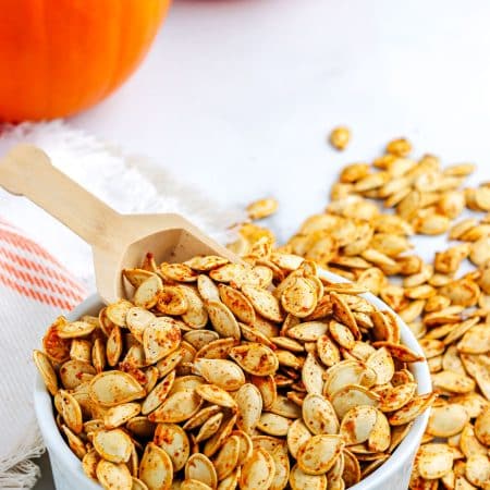 A serving spoon in a bowl of toasted pumpkin seeds.