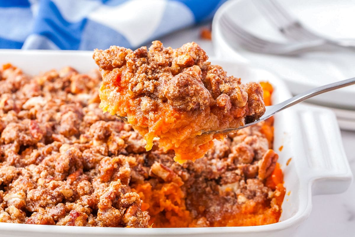 A spoon lifting a scoop of the Gluten-Free Sweet Potato Casserole from the pan.
