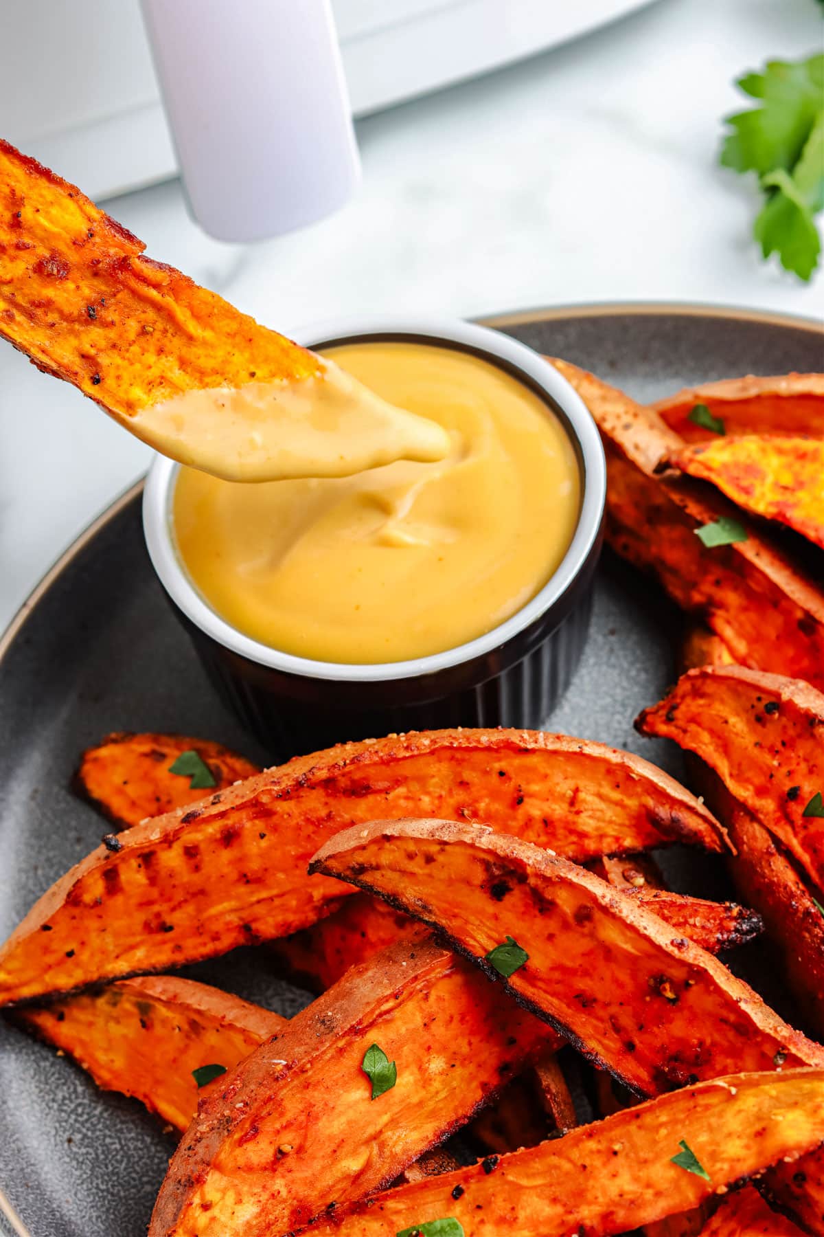Air Fryer Sweet Potato Wedges dipped into a sauce.