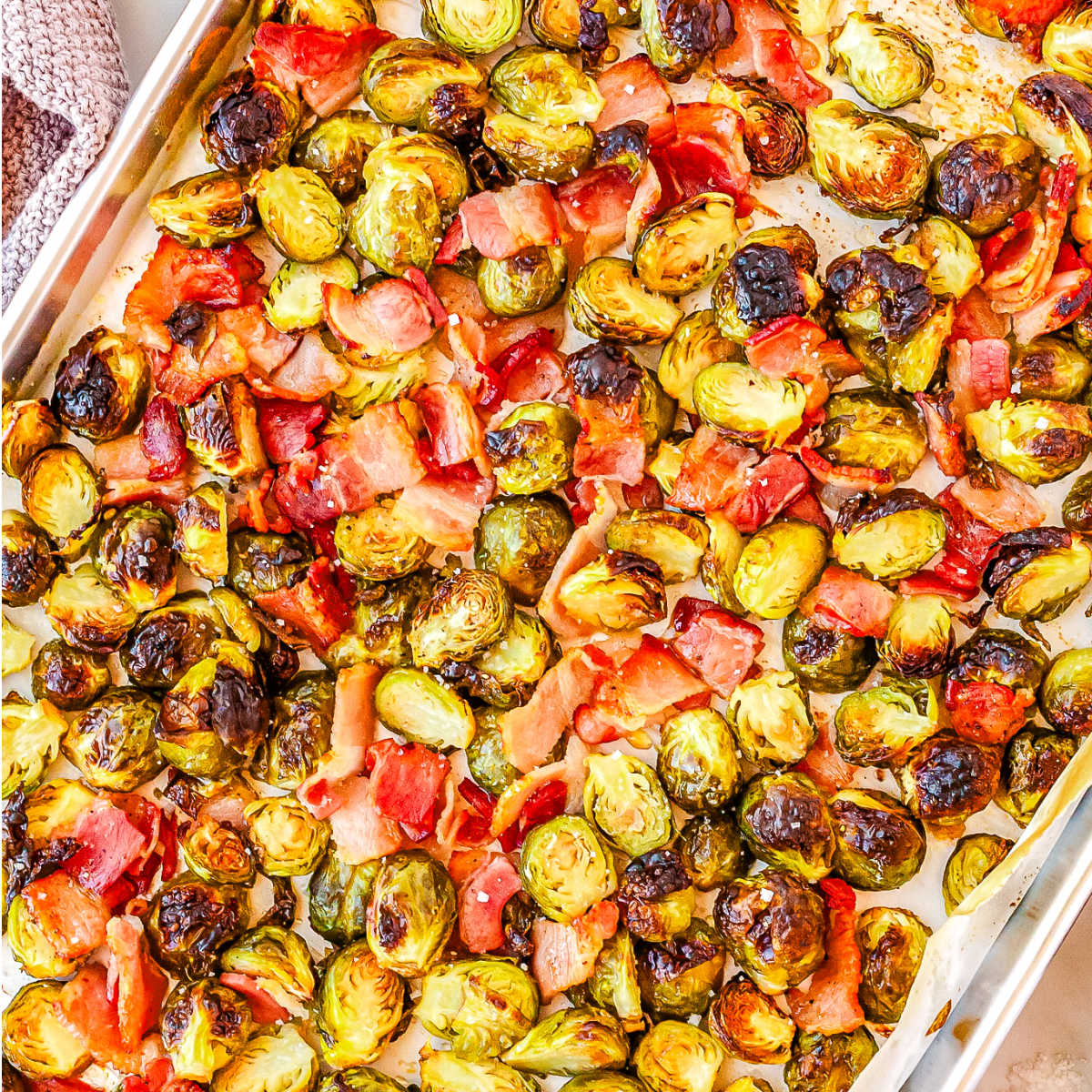 A rimmed baking sheet with roasted Brussels sprouts and bacon.