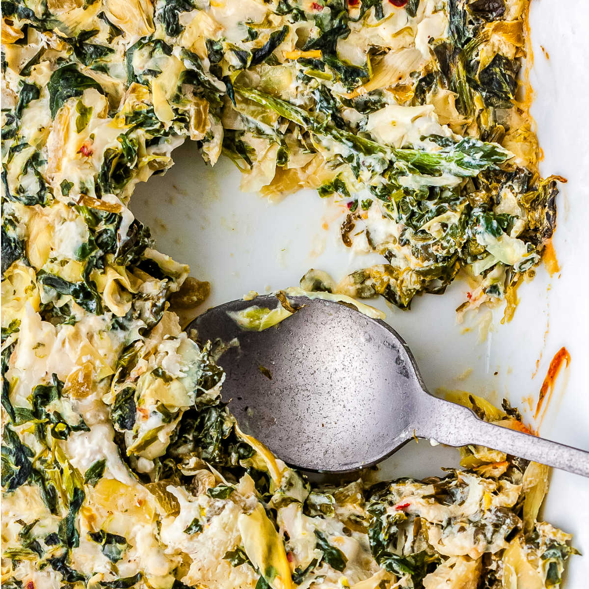 A spoon in the dip ready to scoop it up.