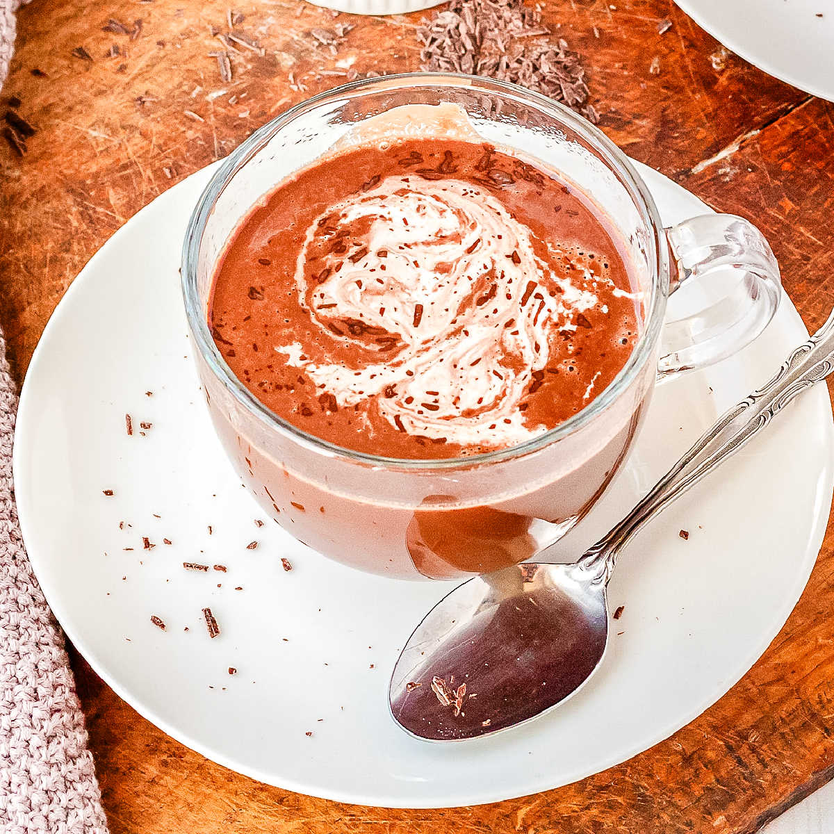 Hot chocolate made with protein powder in a clear glass mug.