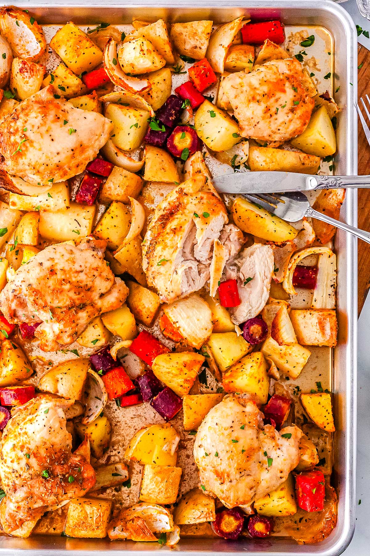 A sheet pan chicken thigh cut into so you can see the juicy interior.
