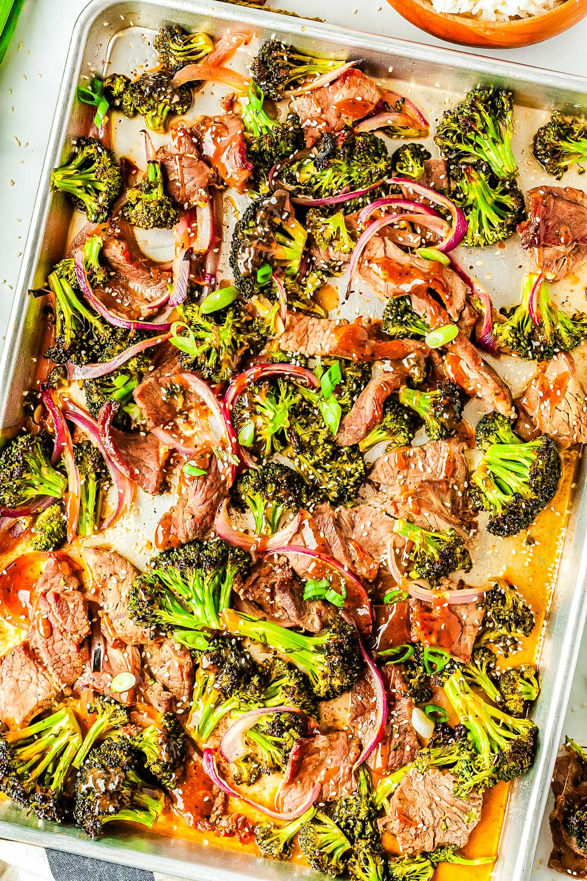 The finished sheet pan beef and broccoli garnished with sesame seeds and green onion.