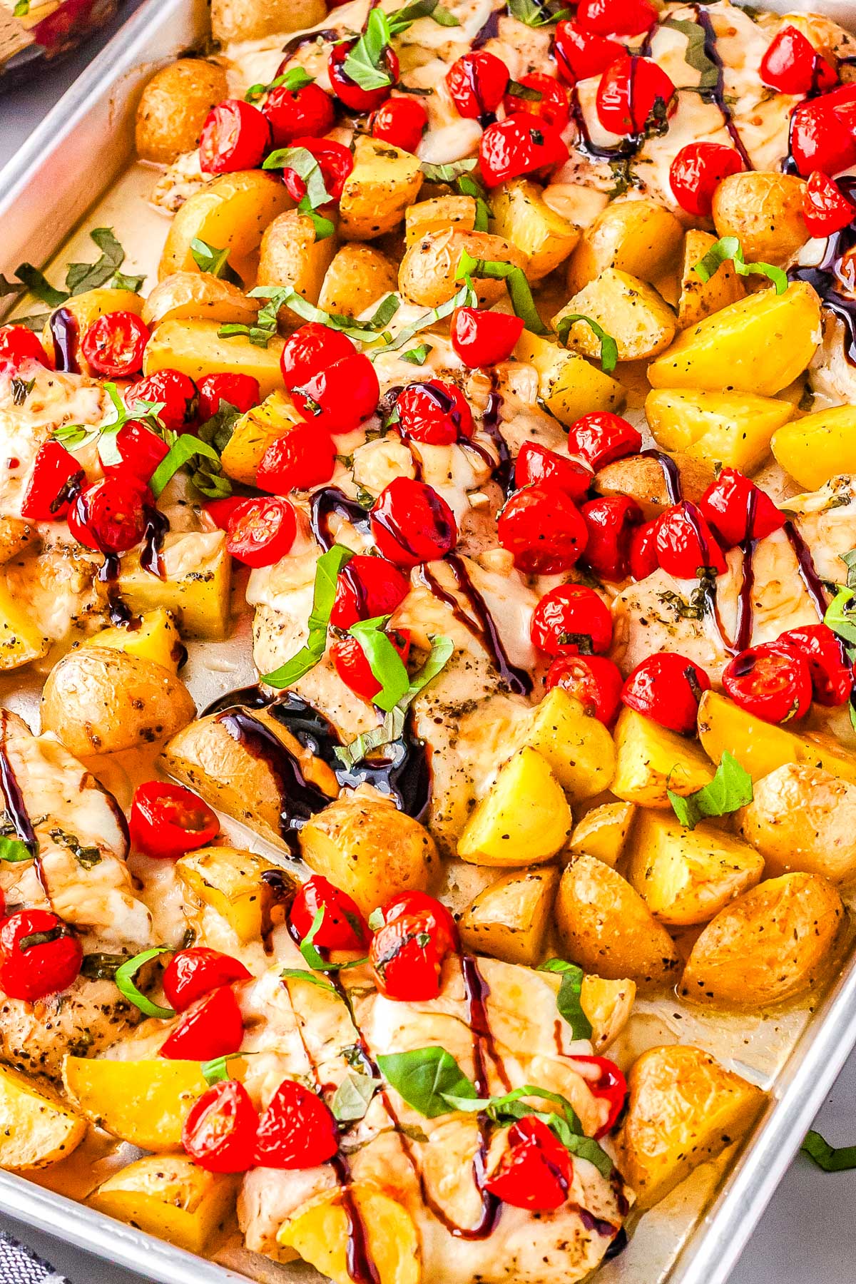 Bruschetta Chicken on a sheet pan drizzles with balsamic glaze.