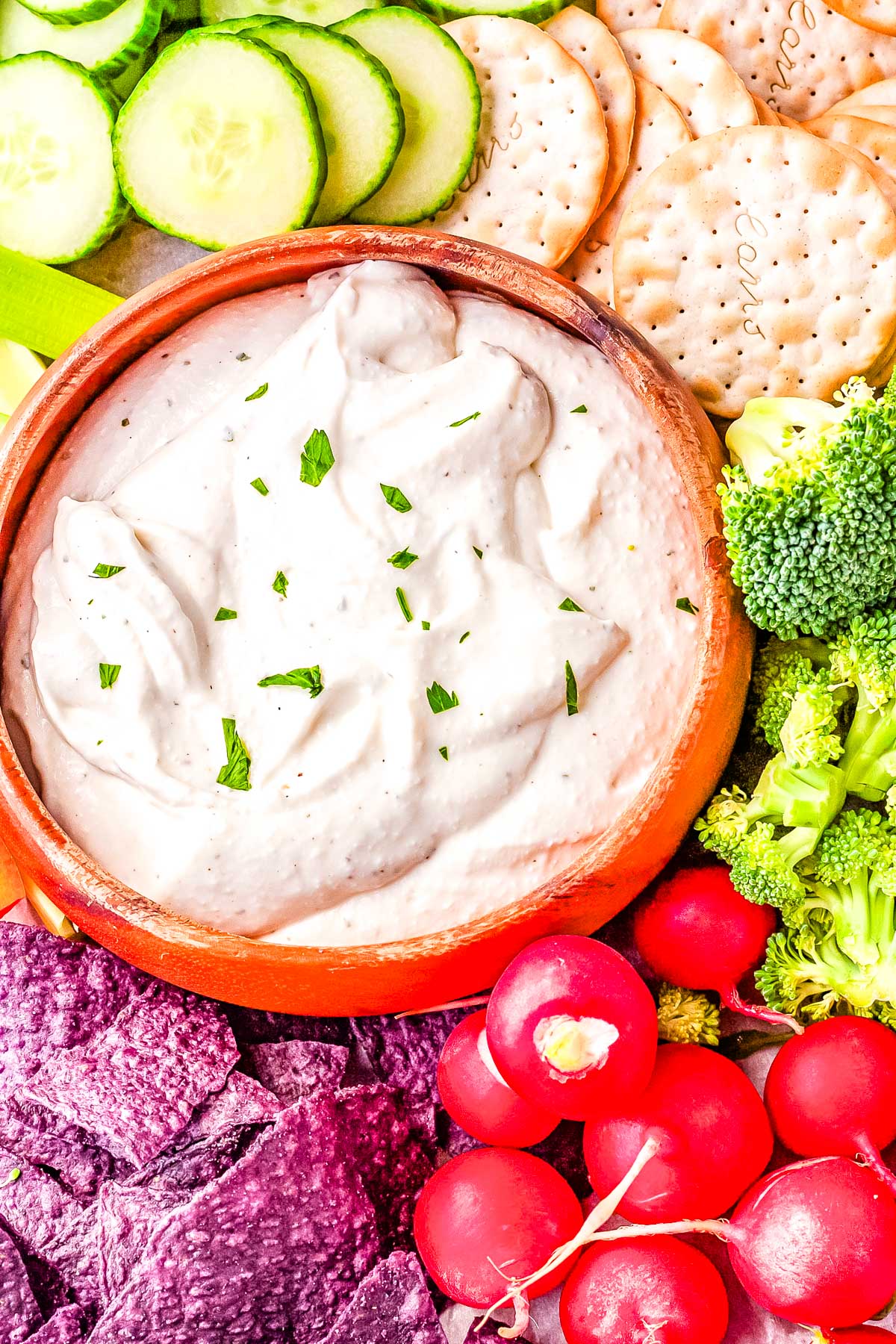 A bowl of Cottage Cheese Ranch Dip surrounded by veggies, totilla chips, and crackers.