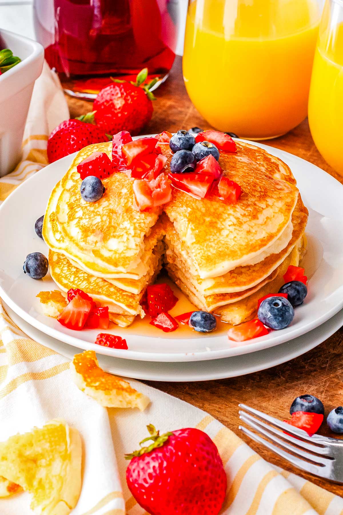 A stack of mochi pancakes on a white plate garnished with fresh berries and maple syrup.