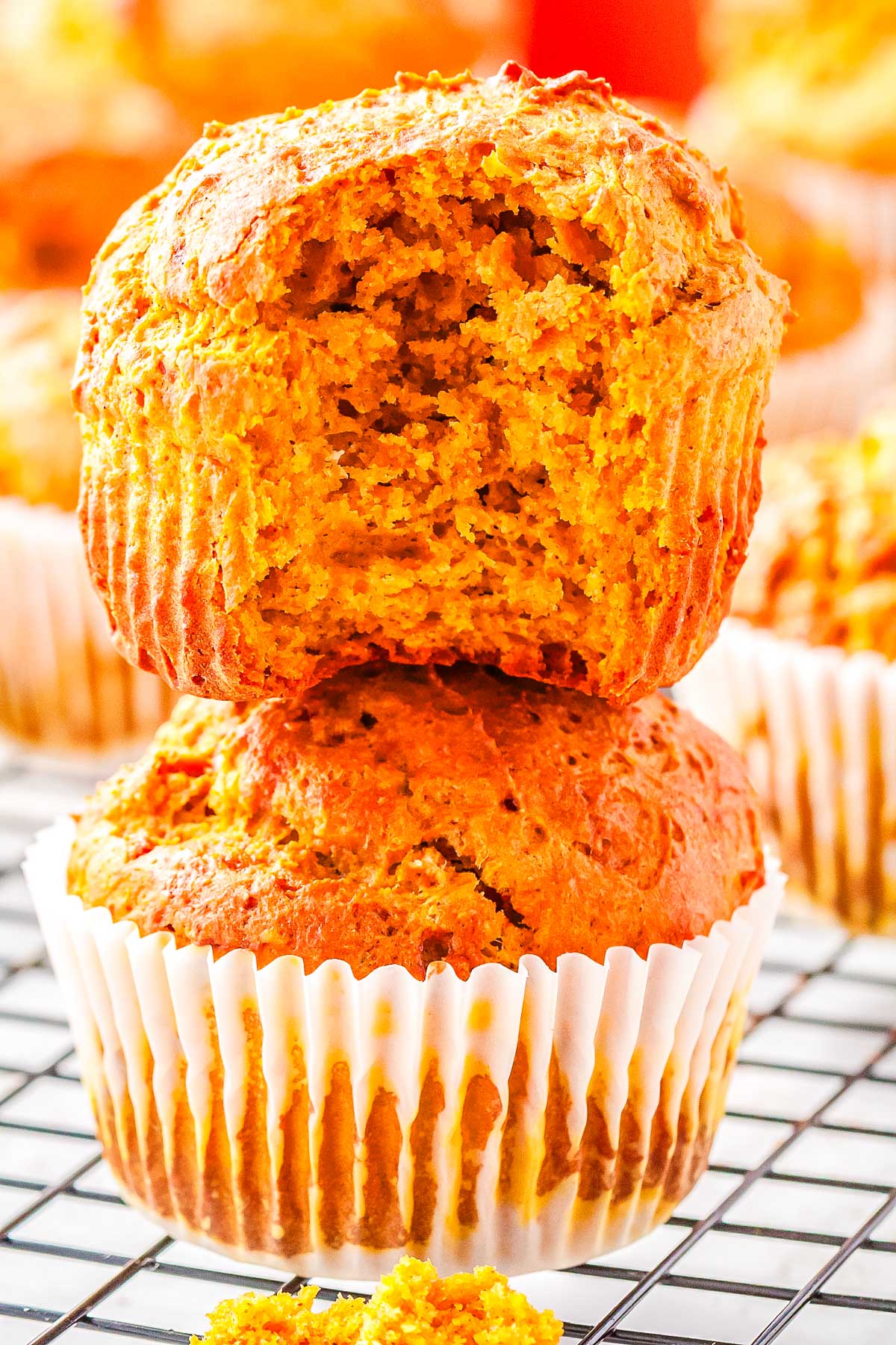 The pumpkin protein muffins stacked on each other with a bite taken out of the top one so you can see the interior.