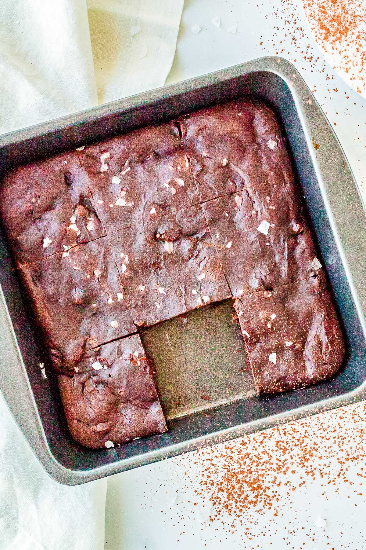 Pan of baked cottage cheese brownies cut into squares and sprinkled with flaky sea salt.
